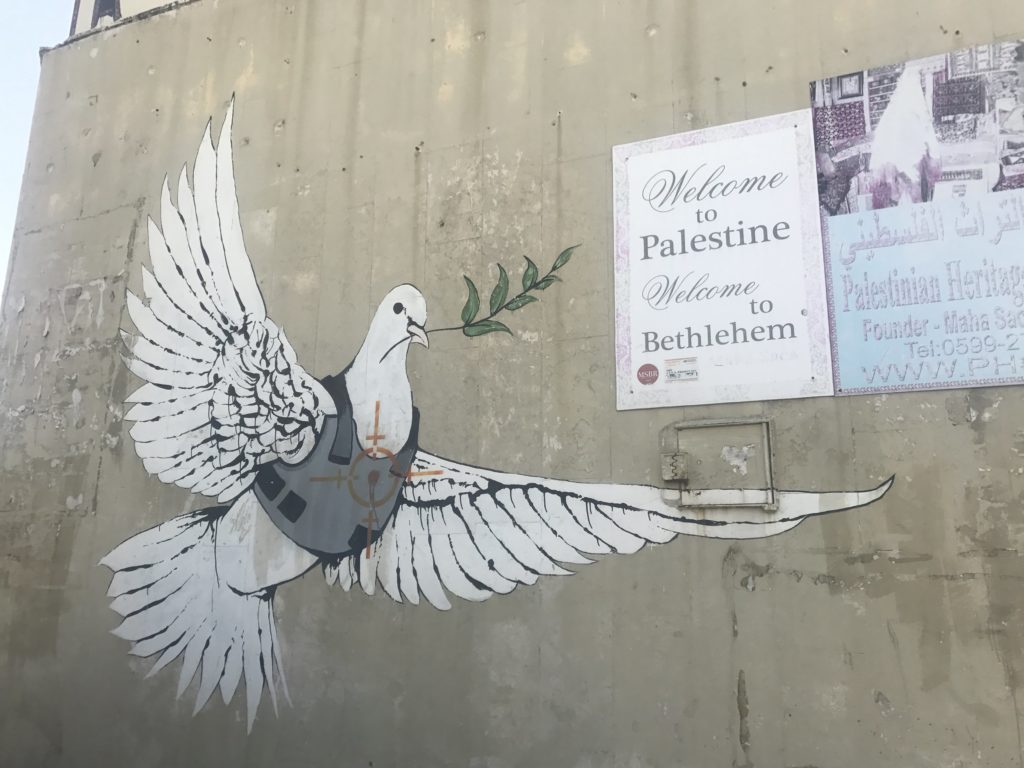 Graffiti wall art in Palestine of a dove of peace wearing a bullet proof vest by Banksy