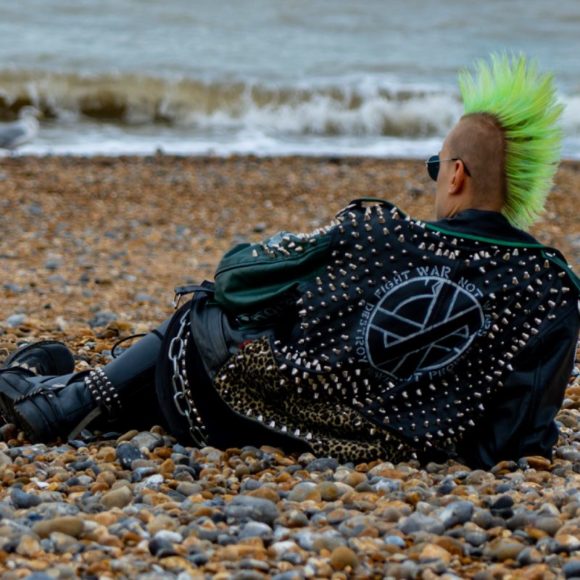 Punk rocker with green irokez/ mohawk hair style relaxes at the beach