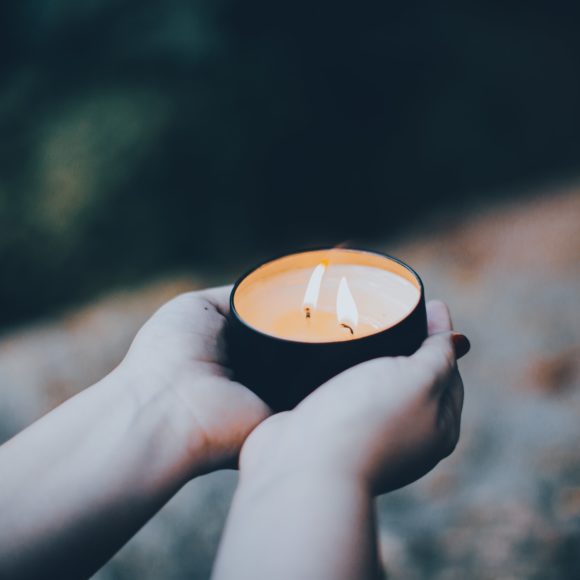 Women's hands holding a candle