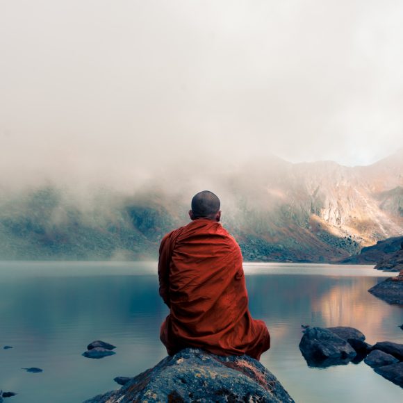 A,Tibetan,Monk,From,Back,Sitting,On,The,Stone,Near